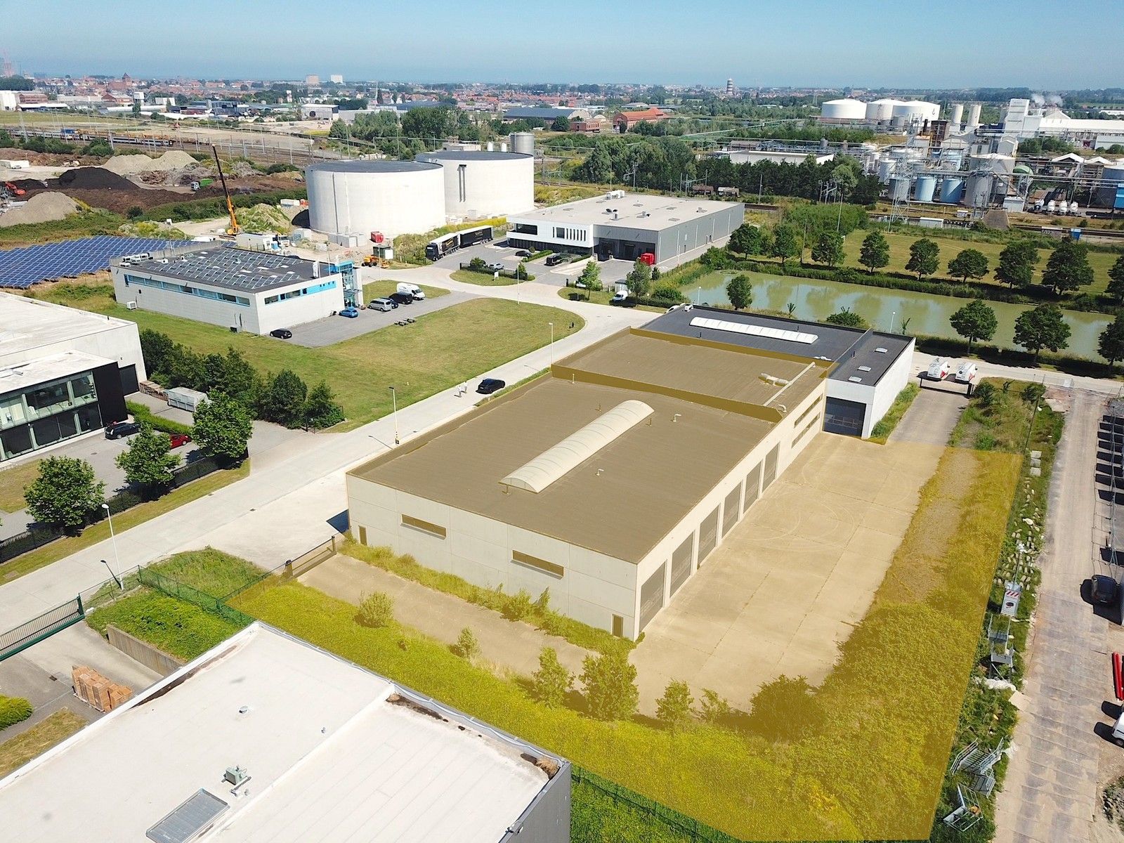 Goed geïsoleerd en verwarmd BEDRIJFSGEBOUW, bestaande uit MAGAZIJN (1.070m2) met KANTOREN en randaccomodatie (770m²)  en 56-tal private parkeerplaatsen op het terrein. Vlak aan de afrit Zandvoorde (Oostende). foto {{pictureIndex}}