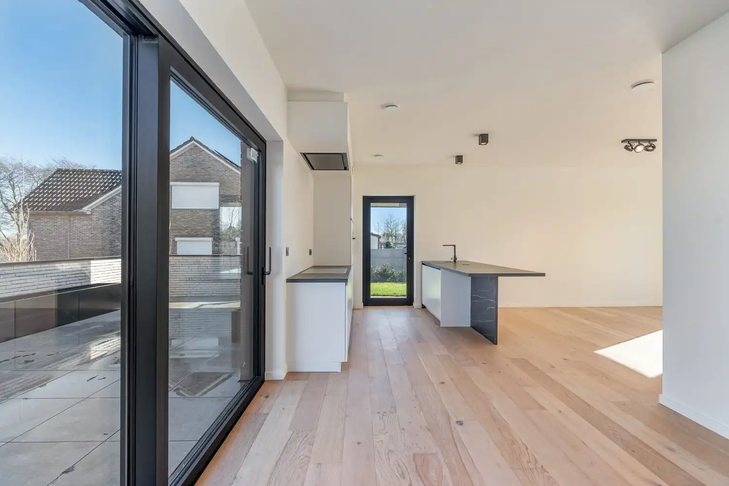 Deze stijlvolle nieuwbouw rijwoning in de Kanunnik Darisstraat combineert een centrale ligging in het hart van Borgloon met hedendaags wooncomfort en energiezuinige technieken. Met winkels, horeca en andere voorzieningen op wandelafstand woon je hier rustig én praktisch.  De woning is verdeeld over twee verdiepen en biedt een doordachte, gezinsvriendelijke indeling. Op het gelijkvloers bevindt zich een gezellige leefruimte met warme parketvloer, die naadloos aansluit op de volledig ingerichte leefkeuken met kookeiland – de ideale plek om te koken, te tafelen en gasten te ontvangen in een aangename, open sfeer.  Op de verdieping zijn er drie volwaardige slaapkamers, waardoor deze woning ideaal is voor gezinnen, koppels die extra ruimte wensen of wie een aparte bureau‑ of hobbykamer zoekt. De stijlvol afgewerkte badkamer, met kwalitatief badkamermeubel, ruime inloopdouche en moderne zwarte accenten, zorgt elke dag opnieuw voor een echt wellnessgevoel.  Buiten geniet je van een... foto 6