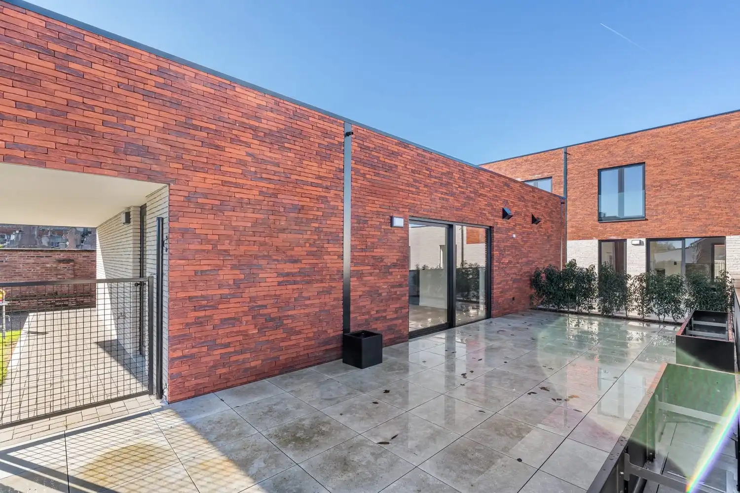 Deze stijlvolle nieuwbouw rijwoning in de Kanunnik Darisstraat combineert een centrale ligging in het hart van Borgloon met hedendaags wooncomfort en energiezuinige technieken. Met winkels, horeca en andere voorzieningen op wandelafstand woon je hier rustig én praktisch.  De woning is verdeeld over twee verdiepen en biedt een doordachte, gezinsvriendelijke indeling. Op het gelijkvloers bevindt zich een gezellige leefruimte met warme parketvloer, die naadloos aansluit op de volledig ingerichte leefkeuken met kookeiland – de ideale plek om te koken, te tafelen en gasten te ontvangen in een aangename, open sfeer.  Op de verdieping zijn er drie volwaardige slaapkamers, waardoor deze woning ideaal is voor gezinnen, koppels die extra ruimte wensen of wie een aparte bureau‑ of hobbykamer zoekt. De stijlvol afgewerkte badkamer, met kwalitatief badkamermeubel, ruime inloopdouche en moderne zwarte accenten, zorgt elke dag opnieuw voor een echt wellnessgevoel.  Buiten geniet je van een... foto 8