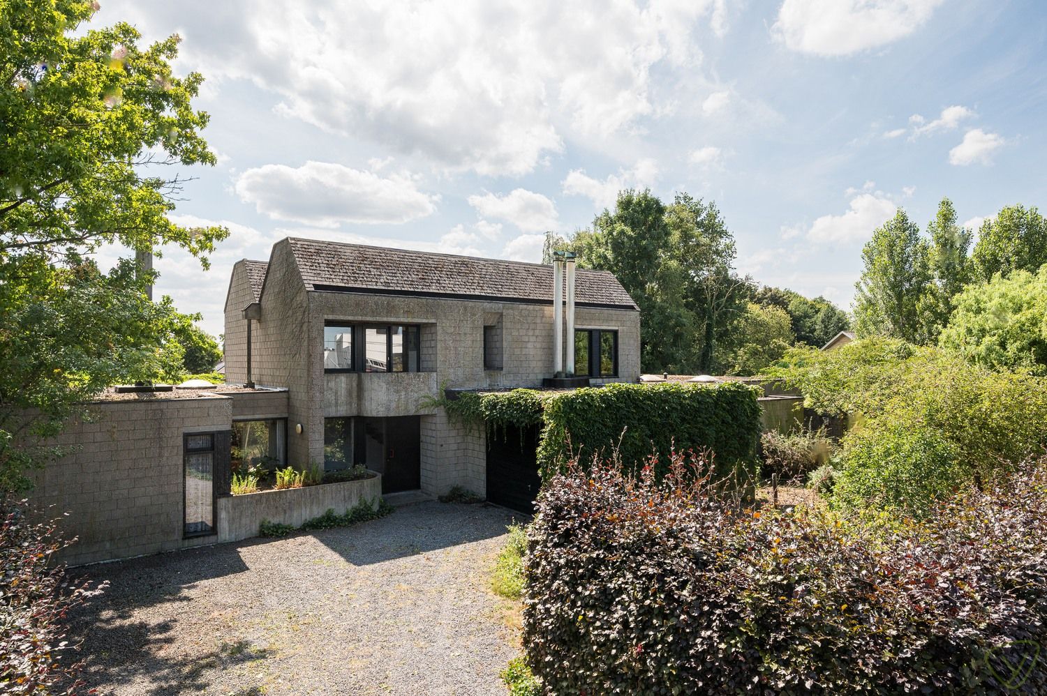 Hoofdfoto van de publicatie: Modernistische parel uit 1978 met brutalistische charme en praktijkruimte op riant perceel in Lembeke