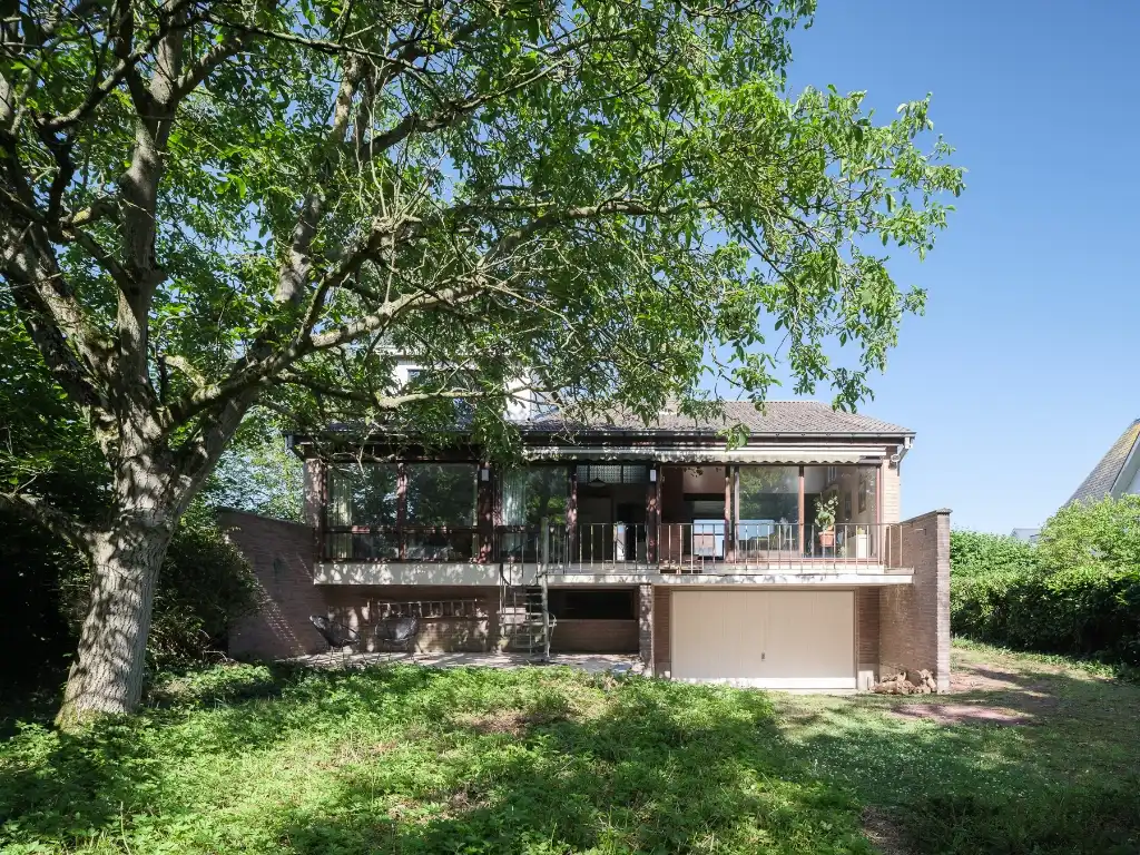 Hoofdfoto van de publicatie: Mid-century modern villa met vier slaapkamers, verdeeld over drie niveaus, gelegen op een groen perceel in Lievegem.