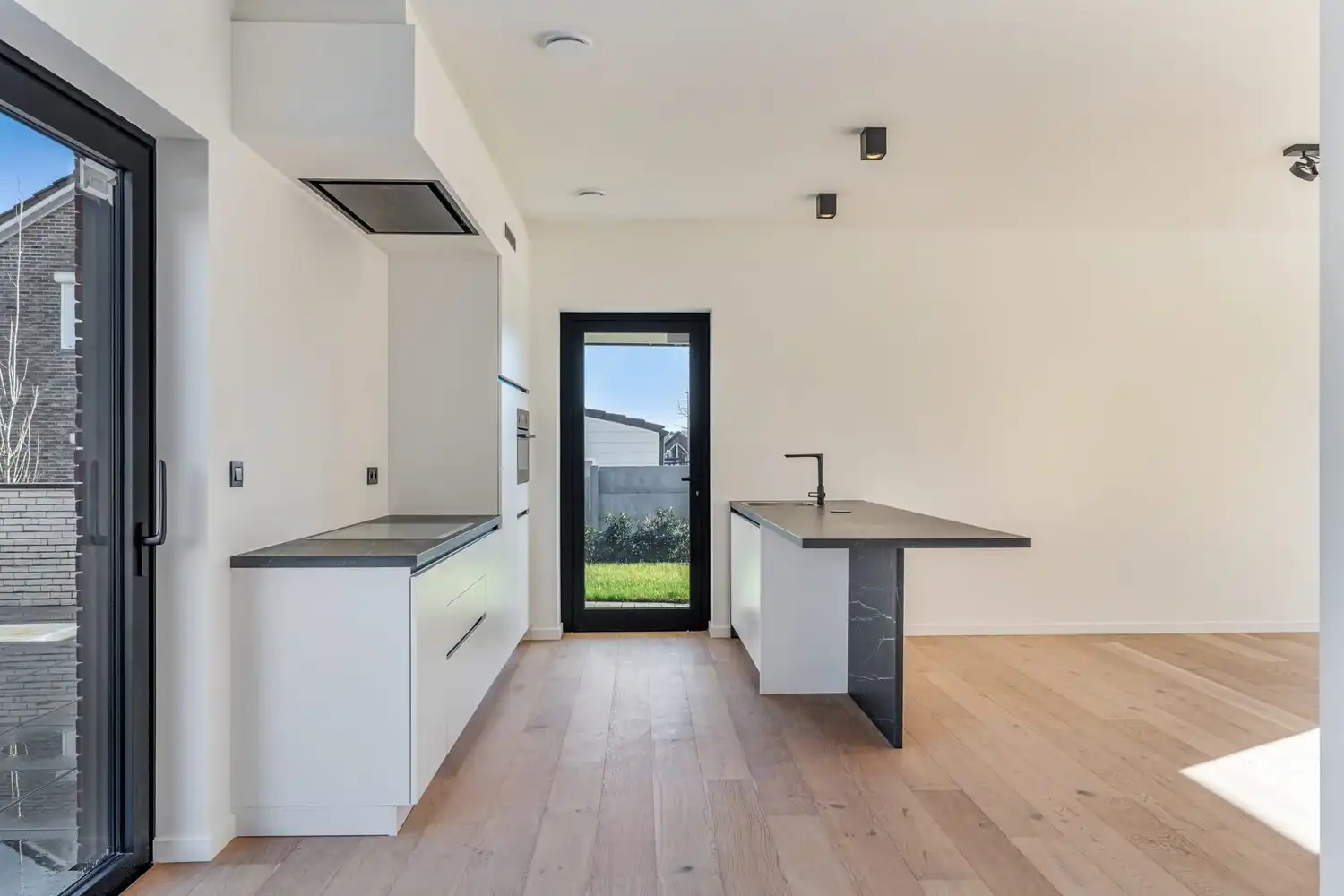 Deze stijlvolle nieuwbouw rijwoning in de Kanunnik Darisstraat combineert een centrale ligging in het hart van Borgloon met hedendaags wooncomfort en energiezuinige technieken. Met winkels, horeca en andere voorzieningen op wandelafstand woon je hier rustig én praktisch.  De woning is verdeeld over twee verdiepen en biedt een doordachte, gezinsvriendelijke indeling. Op het gelijkvloers bevindt zich een gezellige leefruimte met warme parketvloer, die naadloos aansluit op de volledig ingerichte leefkeuken met kookeiland – de ideale plek om te koken, te tafelen en gasten te ontvangen in een aangename, open sfeer.  Op de verdieping zijn er drie volwaardige slaapkamers, waardoor deze woning ideaal is voor gezinnen, koppels die extra ruimte wensen of wie een aparte bureau‑ of hobbykamer zoekt. De stijlvol afgewerkte badkamer, met kwalitatief badkamermeubel, ruime inloopdouche en moderne zwarte accenten, zorgt elke dag opnieuw voor een echt wellnessgevoel.  Buiten geniet je van een... foto 5