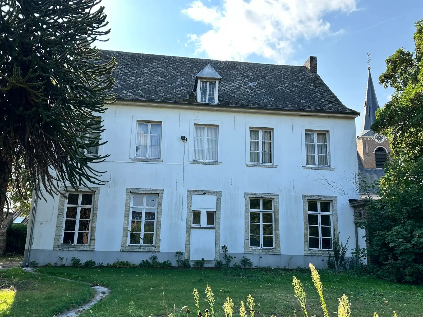 Hoofdfoto van de publicatie: In de schaduw van de kerktoren bevindt zich deze mooie historische idyllische unieke pastorie.  